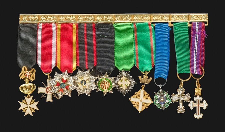 VATICAN – ITALIE – PORTUGAL 
Brochette de 10 miniatures en métal doré, argenté et émail : 
Croix de chevalier de dévotion de l’ordre de Malte, croix du mérite de Malte à titre militaire, étoile de l’ordre de Saint Grégoire le Grand, étoile de l’ordre de Saint Sylvestre, étoile de l’ordre du Saint Sépulcre, étoile de l’ordre de Saint Maurice et Lazare, croix de l’ordre du mérite de la République italienne, étoile de l’ordre de la tour et de l’épée du Portugal, croix de l’ordre de Saint Benoit d’Aviz du Portugal (éclats), croix du mérite militaire du Portugal. 
Barrette en métal doré à décor fleuri. 
T.T.B.