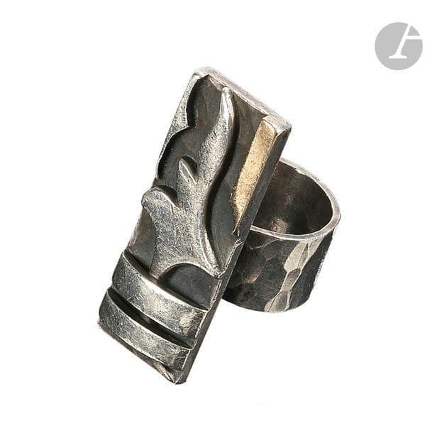 Jean DESPRÉS (1889-1980)
Bague moderniste en argent et or. La platine rectangulaire aux motifs en applications de deux barrettes et d’une forme libre sur fond martelé patiné anthracite. Le large anneau également traité en martelage. Signée J. DESPRÉS à la pointe à l’intérieur de l’anneau et porte les poinçons de Maître Orfèvre et de garantie sur l’anneau. Poids : 21,6 g 

Provenance :
- M. et Mme X., Avallon. Œuvre acquise directement auprès de Jean Després.
- Mme D., Sarzeau (Bretagne). Fille des précédents.