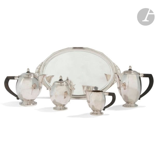 BOUILLET-BORDELLE ORFÈVRE 
Service à thé et café en métal argenté composé des deux verseurs, d’un sucrier, d’un pot à lait et d’un grand plateau ovale à deux prises. Prises et anses en bois noirci. Chaque pièce marquée du poinçon de maître orfèvre. 
H. 19,5 cm - 22 cm - 16,5 cm - 10,5 cm
Plateau : 51 x 33 cm 