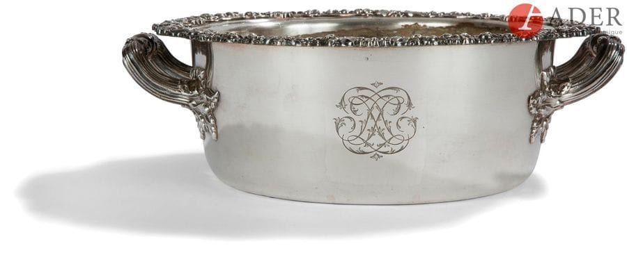 LéGUMIER ET SA DOUBLURE EN MéTAL ARGENTé, LA BORDURE EN ARGENT MASSIF
De forme ronde, il est mouluré de rinceaux feuillagés et coquilles sur le pourtour, les deux anses à larges attaches de feuilles de vigne.Travail français vers 1830 sans poinçon
Diamètre sans les anses : 23 cm - hauteur : 8 cm 
Dans les années 1830, l’orfèvre Gandais déposait un brevet « de métal argenté à garniture argent », qui permettait de faire face aux usures du métal provoqué par le nettoyage des objets en métal argenté. Les parties les plus sollicitées étaient en argent massif. Ce qui est le cas de la bordure de ce légumier.