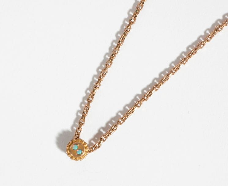 Chaîne en métal, ornée d'un coulant serti de 2 petites opales cabochons.
