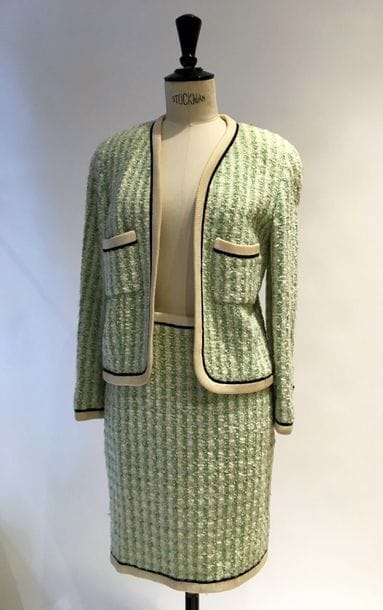 Chanel Boutique. 
Tailleur en tweed sophistiqué laine vert amande, blanc et fibre nacré donnant un effet givré. 2 poches plaquées. Les poches et tous les bords sont gansés de bords côte. Chaîne dorée de lestage. Boutons noirs signés du double C en métal de couleur dorée. T36/38.  (bords jaunis et salissures). Doublure signée. 
On y joint 1 veste à paillettes dans le goût de Chanel.