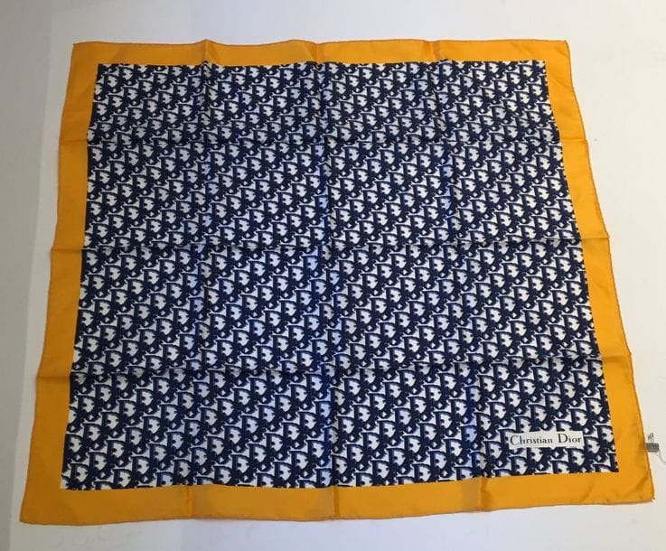 Christian Dior
Carré en soie imprimée du nom Dior sur fond blanc, bordé d'un cadre jaune d'or.
77 x 77 cm. Bel état.
