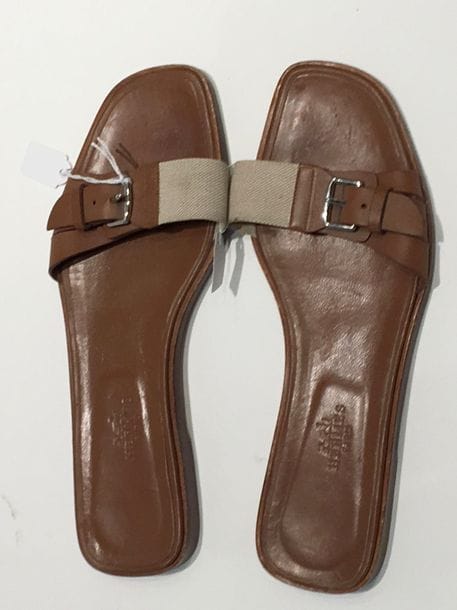 Hermès
Mules claquettes en cuir naturel et toile "H". Etat d'usage. Pointure : 38,5