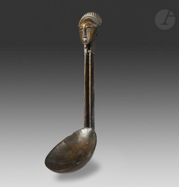 Une très belle cuillère au manche ajouré sur toute sa longueur, surmonté d’un élégant masque environné de décors de lignes crantées. Ce type de cuillère était uniquement la propriété des anciens de haute lignée, et était conservée par eux dans les trésors familiaux. Elles servaient uniquement lors des rituels de sacrifice aux ancêtres pour servir, et leur offrir une nourriture toute symbolique.
Baoule, RCI
Bois, très belle patine d’usage, petit choc mineur au cuilleron.
H. : 17,5 cm