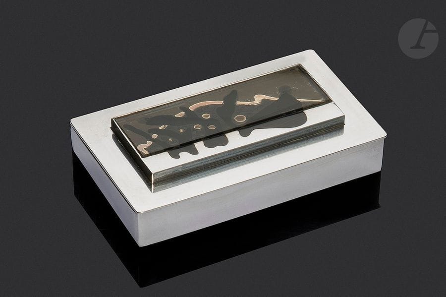 JEAN DESPRÉS (1889-1980) & ÉTIENNE COURNAULT (1891-1948)
Sans titre, circa 1930
Exceptionnelle boîte moderniste en argent.
La base quadrangulaire reçoit un couvercle sur charnières.
Le dessus présente un ressaut central accueillant une œuvre en glace peinte prolongée par une partie en argent poursuivant en laque noire le motif présent sur le verre.
Signée J. DESPRÉS à la pointe et porte le poinçon de Maître Orfèvre sous la base et celui de garantie au revers du couvercle.
Hauteur : 2 cm – Longueur : 8,5 cm – Largeur : 5 cm
Poids brut : 123,9 g

Provenance :
- M. & Mme X., Paris et Courson-les-Carrières, intime de Jean Després. Œuvre acquise directement auprès de l’artiste.
- Œuvre restée dans la descendance des précédents par voie de succession.

Bibliographie :
- Jean Després, maestro orafo tra art deco e avanguardie - Melissa Gabardi, Idea Books, Milano, 1999. Des œuvres de collaboration entre Jean Després et Étienne Cournault reproduites pages 44 à 53.