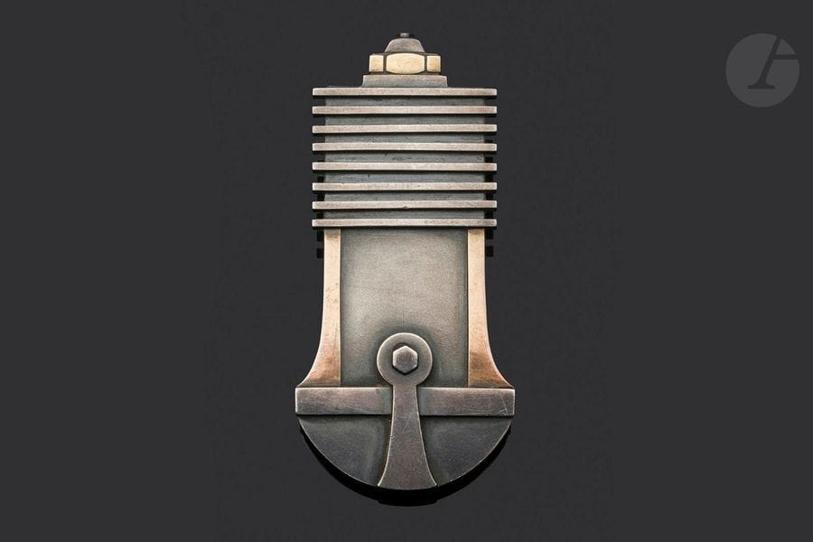 JEAN DESPRÉS (1889-1980) 
Série Bijoux dit Moteurs, circa 1930/35
Exceptionnelle broche en argent et or évoquant un piston, son embiellage et ses segments.
Signée J. DESPRÉS à la pointe au revers et porte le poinçon de garantie.
Hauteur : 6,2 cm
Poids : 20,8 g

Provenance :
- M. & Mme X., Paris et Courson-les-Carrières, intime de Jean Després. Œuvre acquise directement auprès de l’artiste.
- Œuvre restée dans la descendance des précédents par voie de succession.

Bibliographie :
- Jean Després, maestro orafo tra art deco e avanguardie - Melissa Gabardi, Idea Books, Milano, 1999. Notre broche ou un modèle identique reproduit page 61.