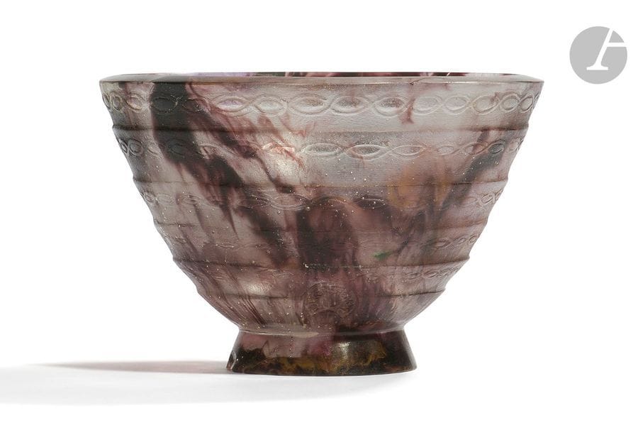 FRANÇOIS ÉMILE DÉCORCHEMONT (1880-1971)
Bol à cinq frises, le modèle créé en [1926], diffusé jusqu’en [1928], réputé avoir été édité à 19 exemplaires
Coupe évasée sur talon tronconique ; le décor en relief de bandes horizontales et de chaînettes.
Épreuve en pâte de verre gris-blanc aux traînées prune et bleu.
Éclats en pourtour de la base.
Marquée du cachet de l’artiste vers la base et porte le numéro B450 sous la base. 
Hauteur : 10 cm 
Diamètre : 15 cm

Bibliographie : 
François Décorchemont, Maître de la pâte de verre – Véronique Ayroles, Éditions Norma, Paris, 2006. Modèle référencé sous le n° 309 page 271, dessin d’archive reproduit sur la même page.