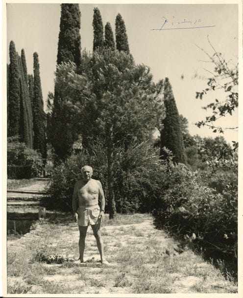 Pablo PICASSO. Photographie avec signature autographe ; 29,5 x 24 cm
Belle photographie originale, d’auteur inconnu, de Picasso, torse nu et en short, dans le jardin de sa maison de Notre-Dame-de Vie à Mougins.
Picasso a signé en haut à droite, dans le ciel, au stylo bille bleu : « Picasso ». Au dos, son épouse Jacqueline a ajouté : « et Jacqueline ».