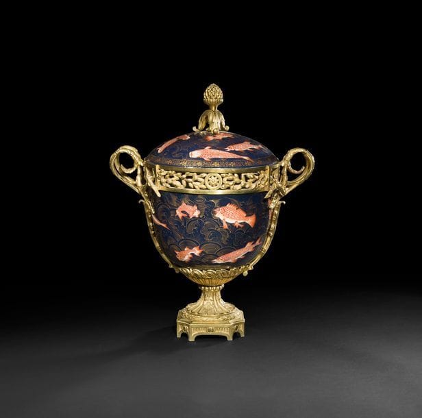 
Grand vase pot-pourri en porcelaine dans le goût de la Chine à décor de poissons rouges sur fond bleu à rehauts d’or, la monture de bronze doré ajouré de feuillages et rosaces, anses doubles et piédouche à godrons et guirlande de feuilles de laurier reposant sur un contresocle.
Style Louis XVI, XIXe siècle.
H : 57 cm, L : 43 cm
