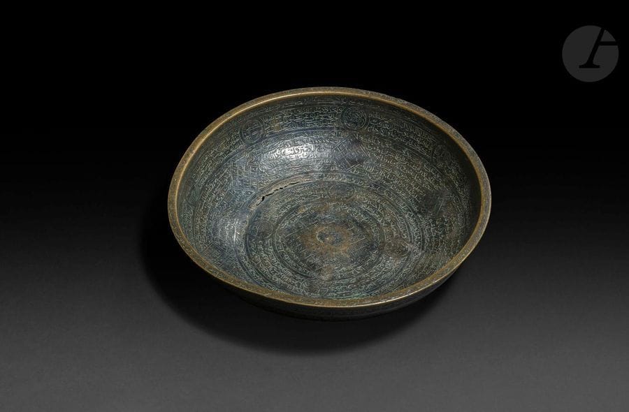 Coupelle magique, Iran qâjâr, XIXe siècle
En bronze patiné orné d’inscriptions divinatoires, de carrés magiques et de médaillons abritant les signes du zodiaque.
Hauteur : 4,5 cm, Longueur : 20 cm
État : bronze fendu au niveau de la base, coupelle déformée.

A bronze magic bowl, Qajar Iran, 19th century