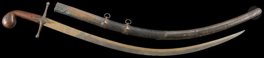 Sabre ottoman qilidj, Turquie ottomane, porte la date de 985H / 1577
Poignée en crosse à plaquettes de bois rivetées. Garde en métal à deux quillons droits achevés en bouton et oreillons losangiques à arête centrale et pourtour ciselé. Lame en acier damasquiné d’or d’un décor de cartouches à inscriptions poétiques en coufique géométrique. L’un d’eux porte la date de 985H /  1577. Un médaillon étoilé indique en écriture cursive le nom du fabriquant : « Amal Asad Allah ». Fourreau en cuir à garnitures en métal à décor repoussé et ciselé de motifs végétaux et géométriques, deux d’entre elles dotées d’un anneau latéral.
Longueur avec fourreau : 103 cm
État : garde mobile, accidents sur le pommeau, garnitures métalliques du fourreau bosselées.

An Ottoman saber qilidj with its leather scabbard, Ottoman Turkey, late 16th century