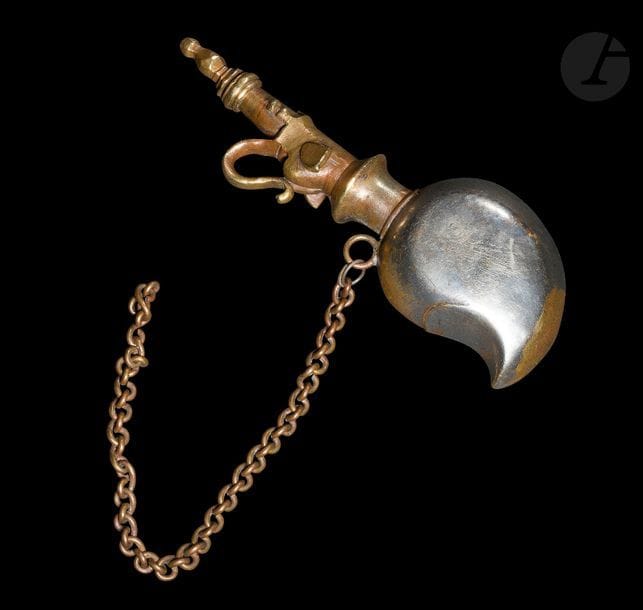 Poire à poudre, Inde du Nord, Rajasthan, XIXe siècle
En métal partiellement doré à déversoir en forme de tête d’éléphant, la trompe recourbée formant un anneau de préhension. Sur la panse en forme de mangue, anneau avec chaîne.
Longueur : 21 cm

A bronze powder flask, North India, Rajasthan, 19th century