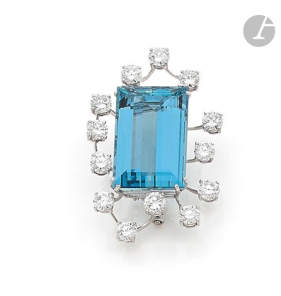 Broche-clip en fils d’or gris 18K (750), orné d’une importante aigue-marine de forme rectangulaire taillée à pans, entourée de 13 diamants ronds. Hauteur : 5,2 cm environ. 
Poids brut : 21,7 g