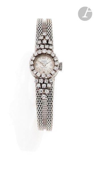 Montre de dame en platine et en or gris 18K (750), cadran rond agrémenté de diamants, les anses soulignées de diamants, bracelet souple en or gris 18K, mouvement mécanique. Travail des années 1960. 
Poids brut : 27,5 g