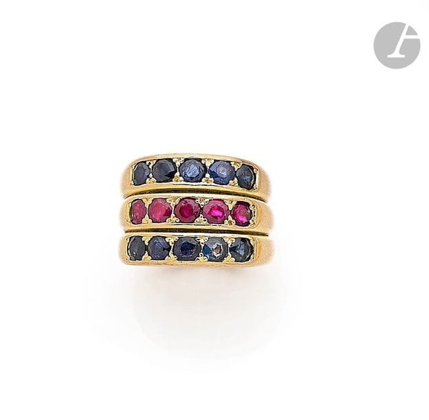 CARTIER (monture). Bague trois corps en or 18K (750), sertie d’une ligne de 5 rubis ronds entre deux lignes de 5 saphirs ronds. Signée et numérotée. Travail français. Tour de doigt : 56 / 57. 
Poids brut : 30,3 g