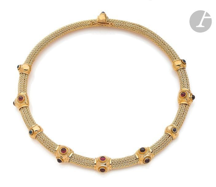 LALAOUNIS. Collier en tresse épaisse d’or jaune 18K (750), ponctué de 9 motifs bombés sertis de saphirs ou de pierres rouges cabochons. Signé. Longueur : 38,5 cm environ. 
Poids brut : 99,5 g