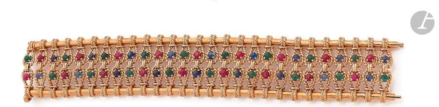 Bracelet large articulé en or 18K (750) cordé et lisse, ponctué de rubis, de saphirs et d’émeraudes cabochons. Travail français des années 1960. Dimensions : 19,5 x 3,2 cm environ.
Poids brut : 101,1 g
Egrisures
