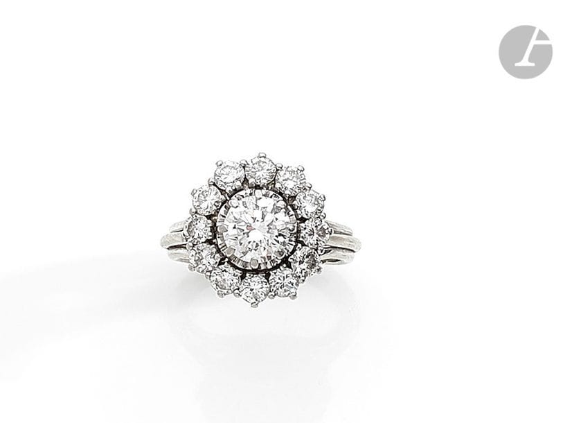 Bague en platine et or gris 18K (750), ornée d’un diamant rond entouré de 12 diamants ronds plus petits. Travail français des années 1960. Tour de doigt : 50. 
Poids brut : 6,6 g