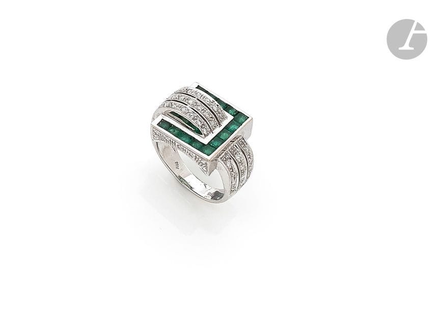 Bague asymétrique en or gris 18K (750) à rouleau, sertie de diamants ronds, et boucle ornée d’émeraudes calibrées. Tour de doigt : 7,9 g