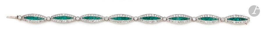Bracelet en or 18K (750) et platine, articulé de 8 maillons ovales sertis d’une ligne d’émeraudes calibrées entre deux lignes de diamants ronds. Longueur : 18,8 cm environ. 
Poids brut : 12 g 