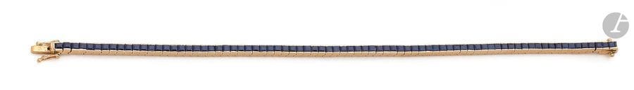 Bracelet ligne en or jaune 18K (750), orné de saphirs calibrés. Longueur : 17,7 cm environ. 
Poids brut : 15,5 g