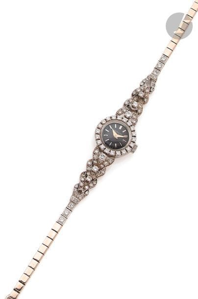GUBELIN. Vers 1950
N°167344
Montre bracelet pour femme en or gris 18K (750), lunette et anses serties de diamants taille brillant, cadran noir index bâtons appliqués formant les heures, mouvement à remontage mécanique No 60702, bracelet a maille plate en or gris 18K.
Cadran, boîtier, mouvement signés.
Poids brut : 20,5 g
Longueur : 17,5 cm
