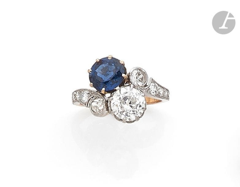 Bague toi et moi en or 18K (750), ornée d’un diamant rond de taille ancienne et d’un saphir rond, l’épaulement serti de diamants ronds. Travail du début du XXe siècle. Tour de doigt : 52. 
Poids brut : 5,2 g (égrisures)