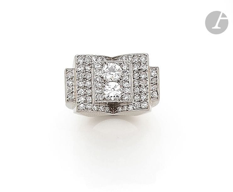 Bague chevalière en platine et en or gris 18K (750) en « livre ouvert », sertie de deux diamants ronds principaux entre des diamants plus petits. Travail français des années 1935. Tour de doigt : 44 / 45. 
Poids brut : 17,6 g (choc)