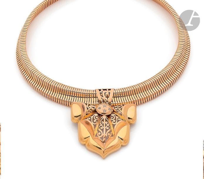 Collier souple en or 18K (750) tubogaz, retenant en pendentif une broche en or 18K dessinant un écusson ajouré, agrémenté de petits diamants ronds. Travail français des années 1940. Longueur : 39 cm environ. 
Poids brut : 65,5 g (déformations)