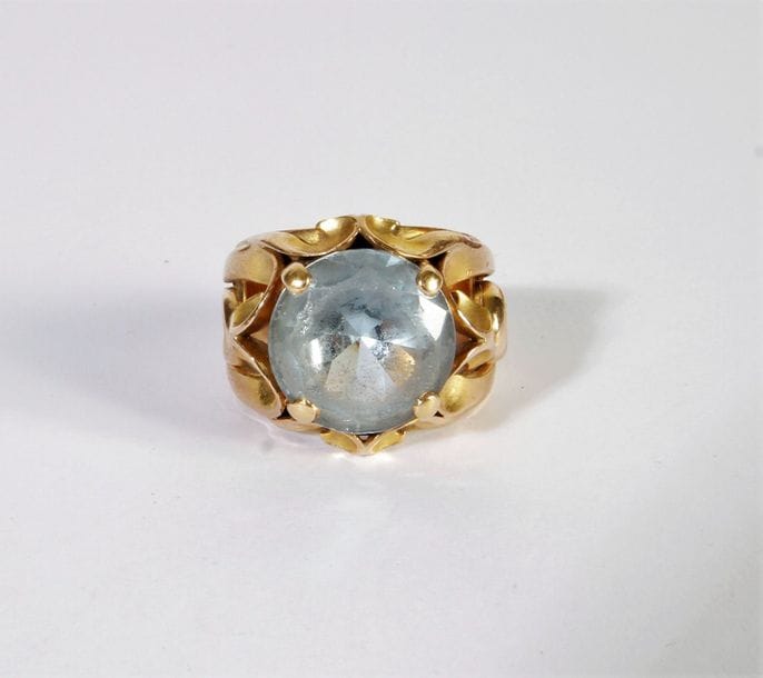 Bague en or 18K (750), l'épaulement ajouré de volutes stylisées, ornée d'une pierre bleue. Poids brut: 11,4 g