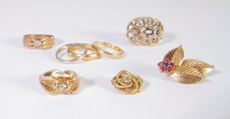 Lot de bijoux et bris d'or 18K (750) comprenant: un clip d'oreille, trois alliances (tours de doigt: 52, 57 et 59), deux montures de bague et une pince à foulard. Poids brut : 36,8 g