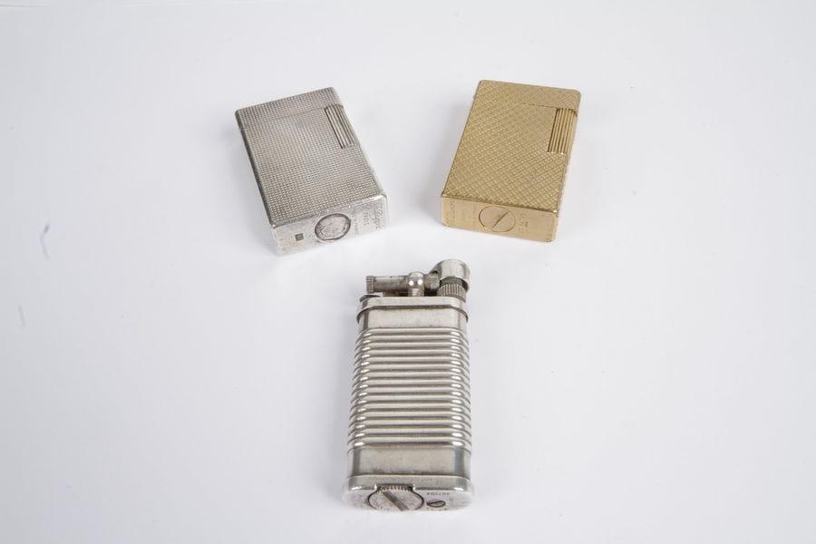 Lot comprenant : deux briquets Dupont, l'un en métal doré, l'autre en métal gris, un briquet Dunhill.