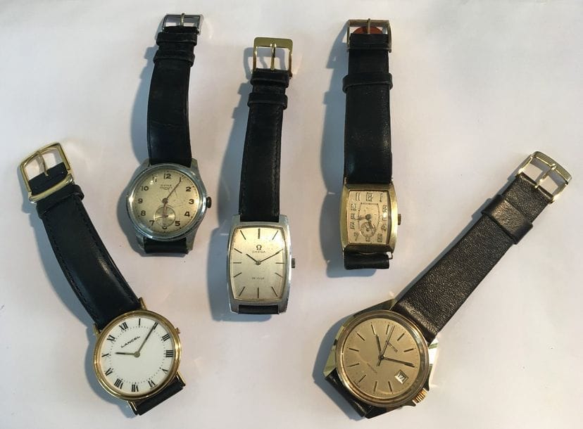 Lot de 5 montres bracelet d'homme : 1 montre en or 18K (750), cadran rectangulaire, chiffres arabes. Poids brut : 23,4 g - et 4 montres en métal : 1 Omega de forme tonneau, 1 Cyma ronde modèle triplex, 1 Lancel et 1 Herma.