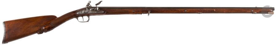 Fin fusil de chasse à silex.
Canon rond à pans au tonnerre gravé sur fond d’or d’un trophée d’armes, de flammes et feuillages. Queue de culasse gravée. Platine signée « Fourni par Pirmet à Paris » et chien col de cygne à corps ronds. Bassinet en fer à volutes et pare étincelles. Garnitures en fer découpé, finement gravé d’une urne, rubans et feuillages. Monture en noyer à long fût. Crosse sculptée d’un animal fantastique, en partie quadrillée, ainsi que le fut. Baguette en fanon.
B.E. (léger fêle au fût). Vers 1760 / 1780.

