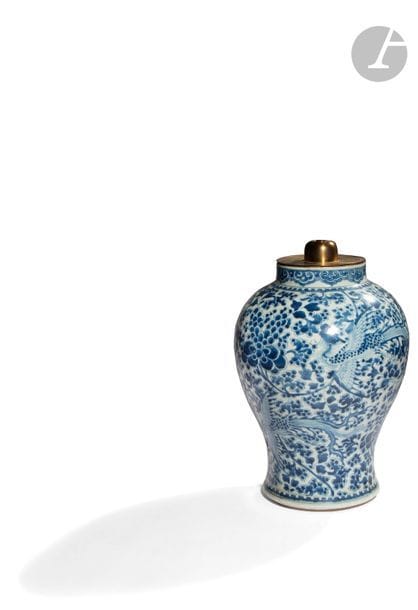 CHINE - XVIIe siècle
Potiche balustre en porcelaine blanche émaillée en bleu sous couverte de phénix parmi les branches de pivoines dans leur feuillage, le col orné d’une frise de lingxi. (éclat en bordure de talon, restauration). 
H. 36,8 cm ; montée en lampe. (état non garanti en bordure de col sous la monture).