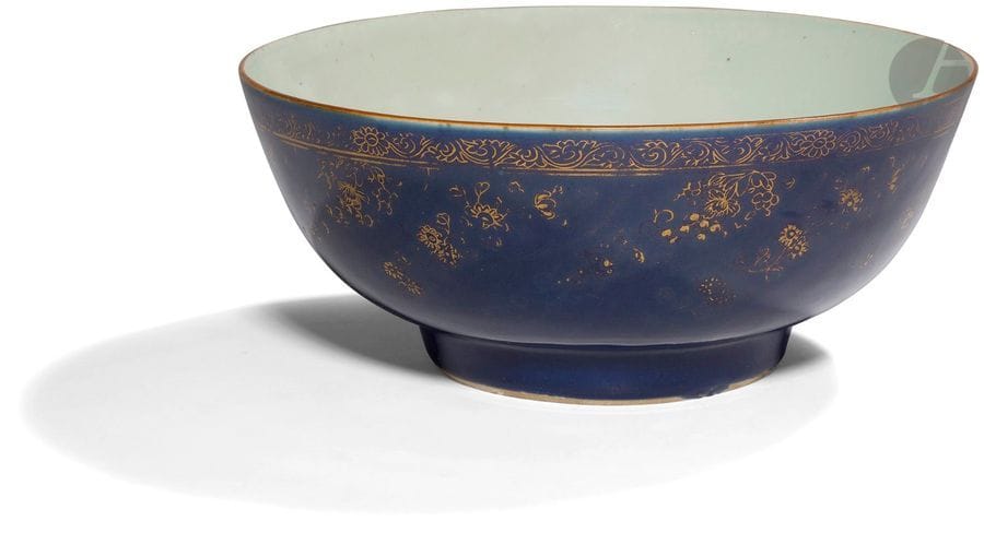 CHINE - XVIIIe siècle
Bol à punch en porcelaine émaillée bleue poudrée ornée de frise de fleurs sur la panse, en rouge de fer à l’intérieur, d’une branche de lotus se dressant. 
Diam. 30,5 cm ; H. 13 cm