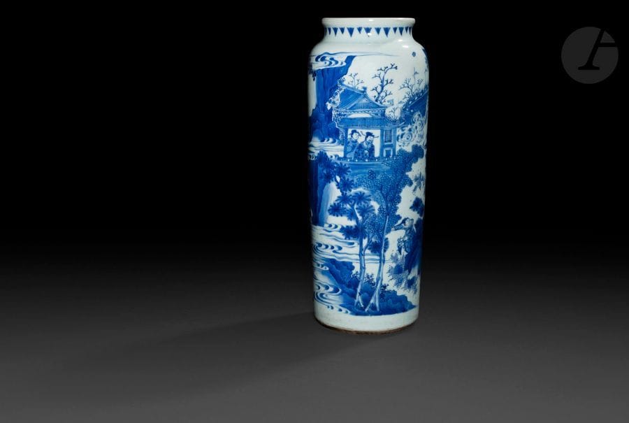 CHINE - XVIIe siècle - TRANSITION
Vase rouleau en porcelaine blanche émaillée en bleu sous couverte d’une scène de combats de guerriers à cheval, tirée des trois royaumes combattants. (Fêlure en étoile au revers se prolongeant sur deux parties visible du vase, bulles de cuisson). 
H. 41,4 cm