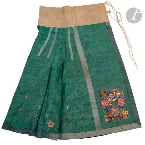 CHINE - XIXe siècle
Jupe (Mamianqun) en soie vert foncé, damassée des fleurs de quatre saisons, à décor brodé aux fils polychromes des pivoines et vases.
On y joint six pièces en soie brodée.