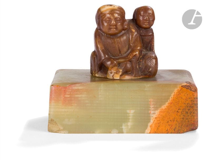 JAPON - Époque MEIJI (1868 - 1912)
Okimono en corne de buffle, Daikoku assis, un enfant derrière lui. 
H. 4,2 cm ; socle en serpentine.