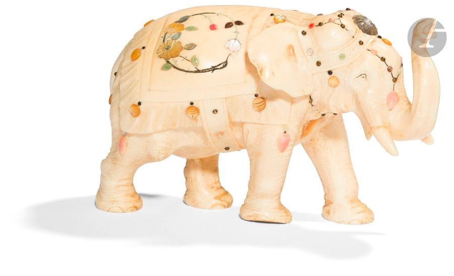 JAPON - Époque MEIJI (1868 - 1912)
Okimono en ivoire, éléphant marchant. À décor d’incrustations de nacre et de pierres dures sur la selle et la tête. 
H. 8,5 cm ; L. 13,5 cm
