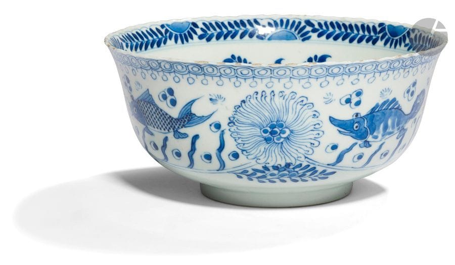 CHINE - Époque KANGXI (1662 - 1722)
Bol à bordure chantournée en porcelaine blanche émaillée en bleu sous couverte de carpes nageant parmi les algues. Au revers la marque Kangxi nianzhi en bleu sous couverte. (égrenures). 
Diam. 20,7 cm
