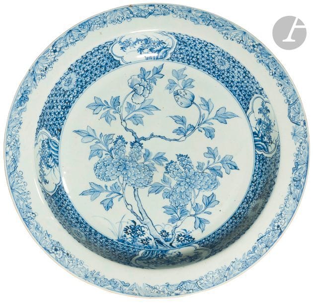 CHINE - XVIIIe siècle
Plat rond en porcelaine blanche émaillée en bleu sous couverte à décor central de branches de fleurs épanouies et en bouton, de branches de fleurs dans des panneaux polylobés en réserve sur fond de fleurons.
Diam. 42,5 cm