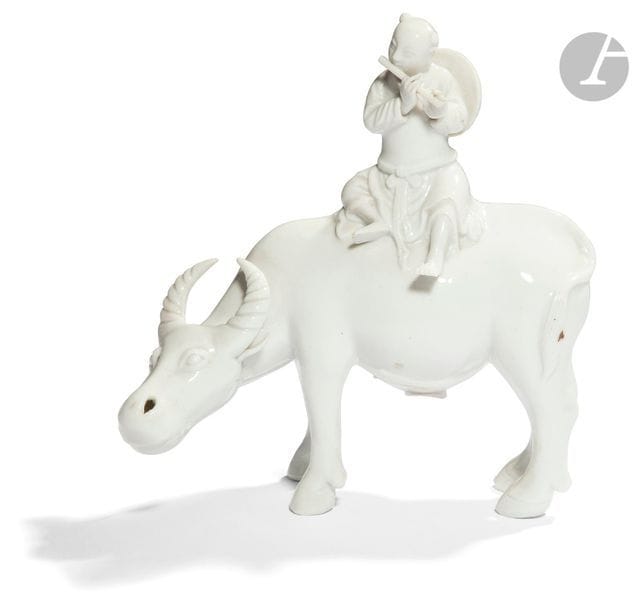 CHINE - XXe siècle
Statuette en porcelaine blanche, La Yuesheng jouant de la flûte assis sur son buffle, symbole d’harmonie parfaite entre l’homme et l’animal. (Manque un doigt). 
H. 19 cm