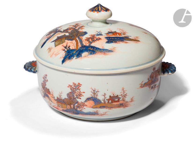JAPON - XVIIIe siècle
Soupière couverte en porcelaine émaillée en bleu sous couverte, rouge de fer et or à décor dit « imari », d’un paysage jonché de cabanons au bord de la rivière, les anses en forme de kiku, la prise du couvercle ornée d’une fleur de chrysanthème. 
H. 19,5 cm ; socle en bois.