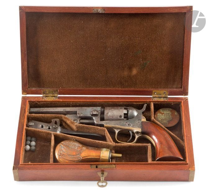 Revolver Colt Pocket modèle 1849, 6 coups, calibre 31.
Canon à pans de 12,6 cm
Avec marquages « address col. sam colt newyork U.S. America ».
Barillet gravé de scène de diligence. Carcasse ouverte frappée colts patent.
Pontet en laiton argenté (restes).
Plaquettes de crosse en noyer.
Finition bleuie patinée.
Dans un coffret en acajou verni, avec moule à balle Colt, poire à poudre à l’aigle et boîte à capsules.
A.B.E.
N°215289. Produit de 1850 à 1872 à 325 000 exemplaires.