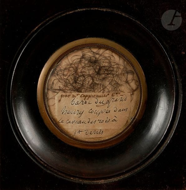 Poils de barbe attribués au Roi HENRI IV 
provenant de M. Jean Augustin Capperronnier, conservateur des livres imprimés du Roi louis xviii.
Présentés sous verre avec billet manuscrit à la plume « par Mr Cappronier Cer - barbe du grand Henry coupée dans le caveau des Rois à St Denis ».
Au dos une notice manuscrite : 
Barbe du grand Henry IV roi mort en 1610 à l’âge de 57 ans. Elle fut donnée à Mr J, Atin, Cappronnier, Ader et Conserveur de la Bibliothèque du Roi Louis XVIII. Par son collègue M. Langlès, qui au moment de la violation des tombeaux des rois à St Denis, en était alors le gardien nommé par la convention nationale, n’ayant pu en empêcher la profanation a (…) en grâce, une pincée de cette barbe dont cette partie a été donnée par lui-même à son intime ami et collègue M. Cappronnier, mort Conser le mois de novembre 1820 à Paris.
B.E. (légèrement insolé, pas de trace d’ouverture du cadre). 

 Historique : 
M. Cappronnier était le conservateur des livres imprimés du Roi et L. Langlès, conservateur-administrateur des manuscrits orientaux de la bibliothèque du Roi.

La profanation des tombes royales de la Basilique de Saint Denis eut lieu d’août 1793 à janvier 1794. 
Le cercueil d’Henri IV fut ouvert le 12 octobre 1792, le corps très bien conservé fut exposé jusqu’au 14 octobre. Nombre de reliques comme les cheveux, les ongles ou les poils de barbe furent prélevées entre-temps. 

Biographies :
Jean-Augustin Capperonnier (1745-1820)
Neveu de Jean, fils de Claude-Augustin, tanneur, Jean-Augustin Capperonnier est appelé en 1765 à la bibliothèque par son oncle Jean, dont le fils, Claude-Marie, n’a encore que sept ans. Sous-garde des imprimés et bibliothécaire du duc de Paulmy en 1780, il accède à la fonction de conservateur lors de la réforme de 1795 et dirige par deux fois l’établissement, de 1796 à 1798 et de 1800 à 1803 suivant le système alors en vigueur d’un « primus inter pares » au sein du Directoire. Il reste fidèl