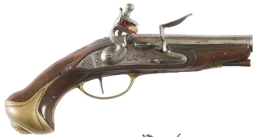Petit pistolet à silex d’officier. 
Canon rond à méplat sur le dessus et bourrelet à la bouche. Platine à corps plat gravé d’un trophée d’armes et de rinceaux. Contre-platine à décor en suite. Chien col de cygne à corps rond et pied de renfort. Garnitures en laiton découpé, gravé, ciselé. Pommeau orné d’une tête de lion. Crosse en noyer sculpté. 
Longueur : 21 cm 
B.E. France, vers 1760-1780.