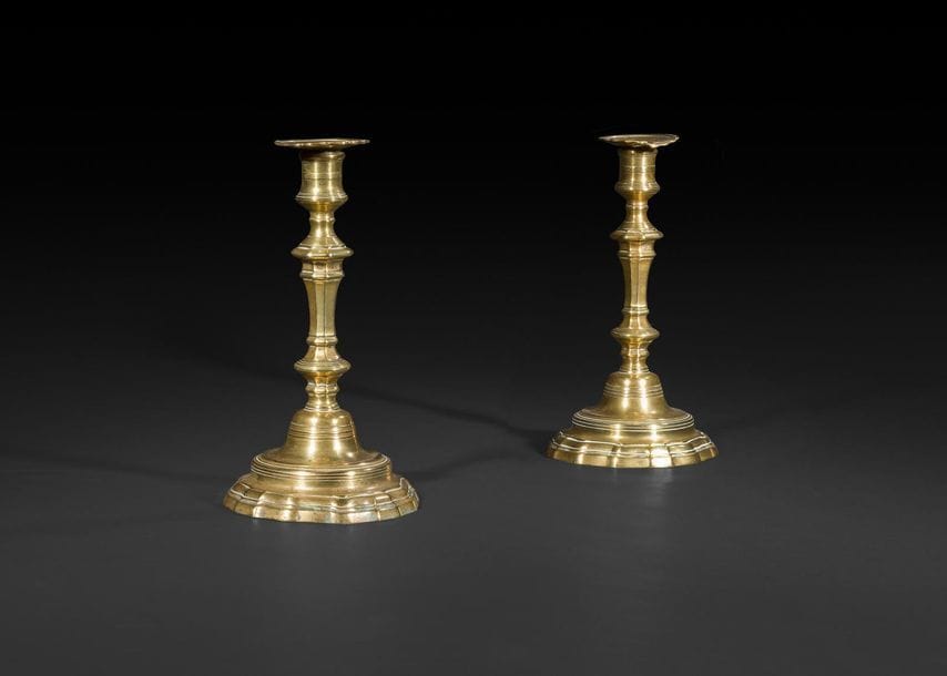Paire de flambeaux en laiton, le fût bagué à pans coupés, reposant sur une base contournée ; (anciennement argentés). 

XVIIIe siècle (restaurations).

H : 25 cm