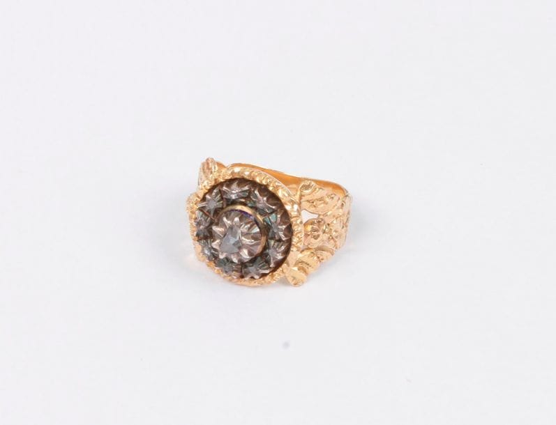 Bague en or 18K (750), le chaton en argent serti de diamants taillés en roses, l'épaulement ciselé de feuillages ciselés. Tour de doigt : 58. Poids brut : 11,3 g (accidents)